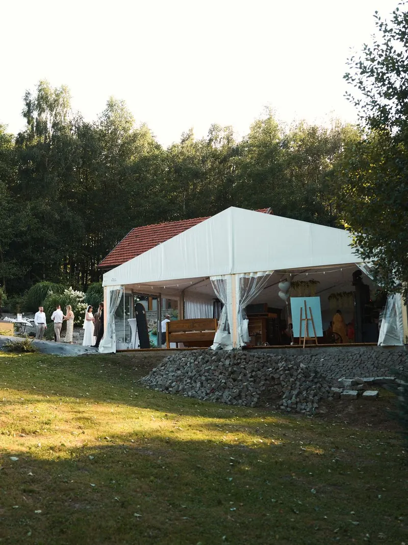 Biały namiot i dom wśród drzew w letnim słońcu
