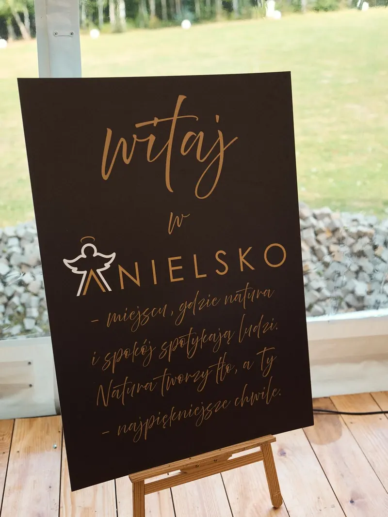 Tablica „Witaj w Anielsko” na drewnianym podeście