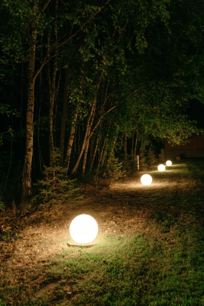 Świecące kule wzdłuż leśnej ścieżki nocą